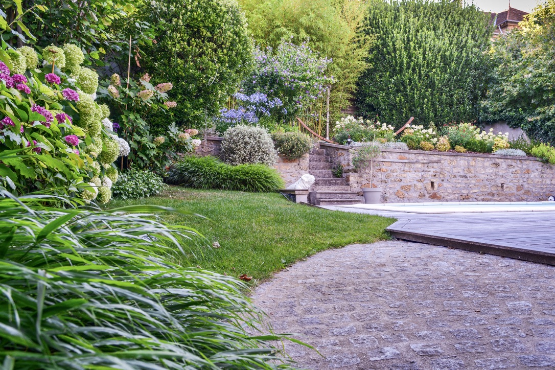 Cheminement pavé, pelouse et terrasse bois au pied de l’escalier en pierre à Juvisy-sur-Orge